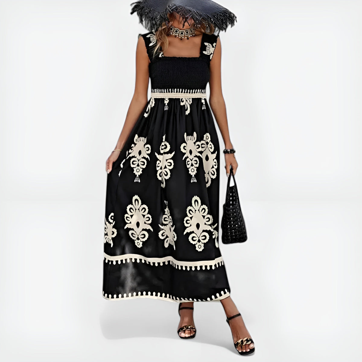 Robe d’été noire sans manches, motifs blancs baroques, taille smock et ourlet contrasté.