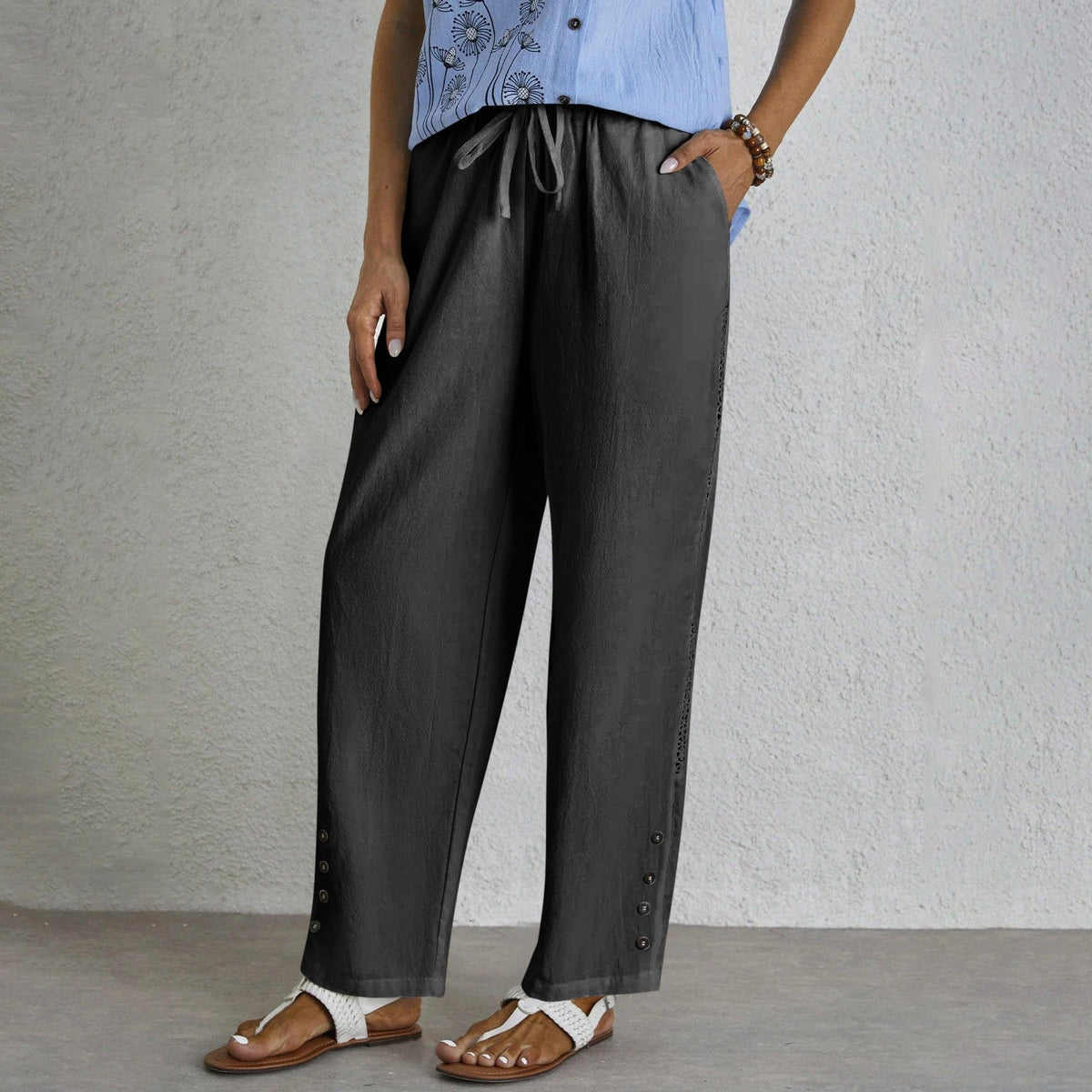 Pantalon ample gris foncé avec cordon à la taille, boutons latéraux et ourlet ajouré