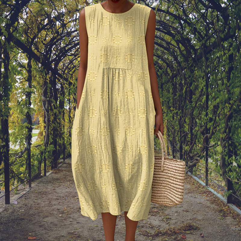 Robe sans manches jaune pâle à broderies florales, jupe à volants et longueur mi-mollet.