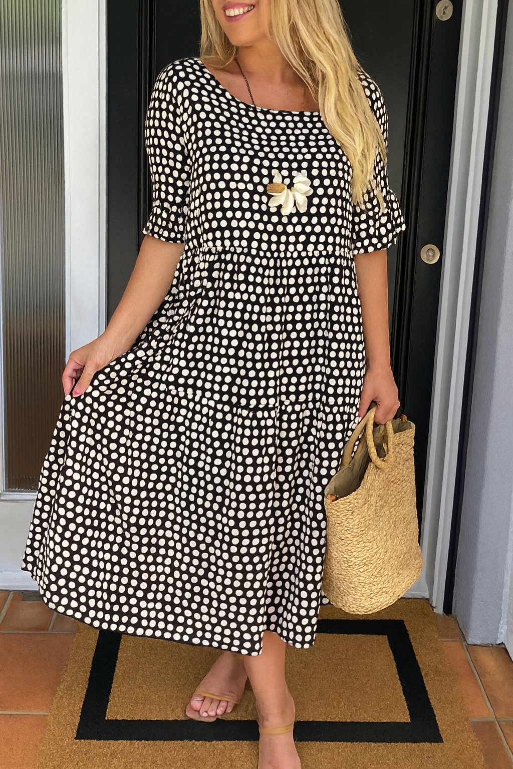 Robe midi fluide noire à pois blancs, manches courtes, fleur brodée au buste, coupe évasée.