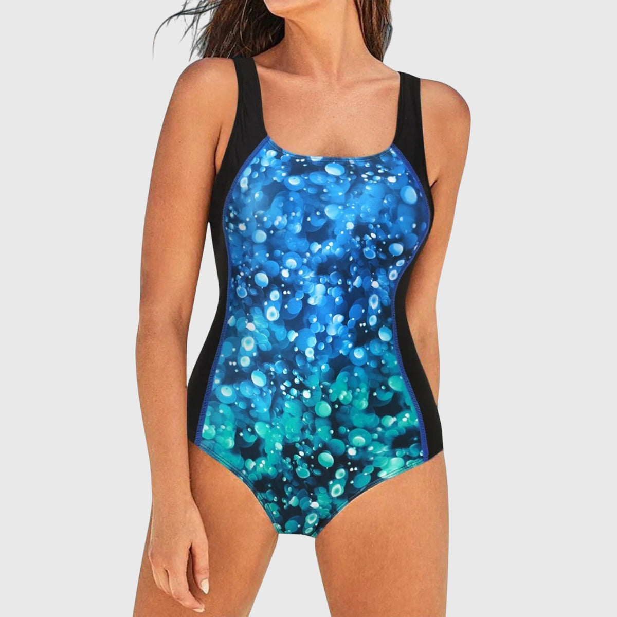 Maillot de bain une pièce bleu à motifs bulles, bretelles noires et ouverture échancrée.