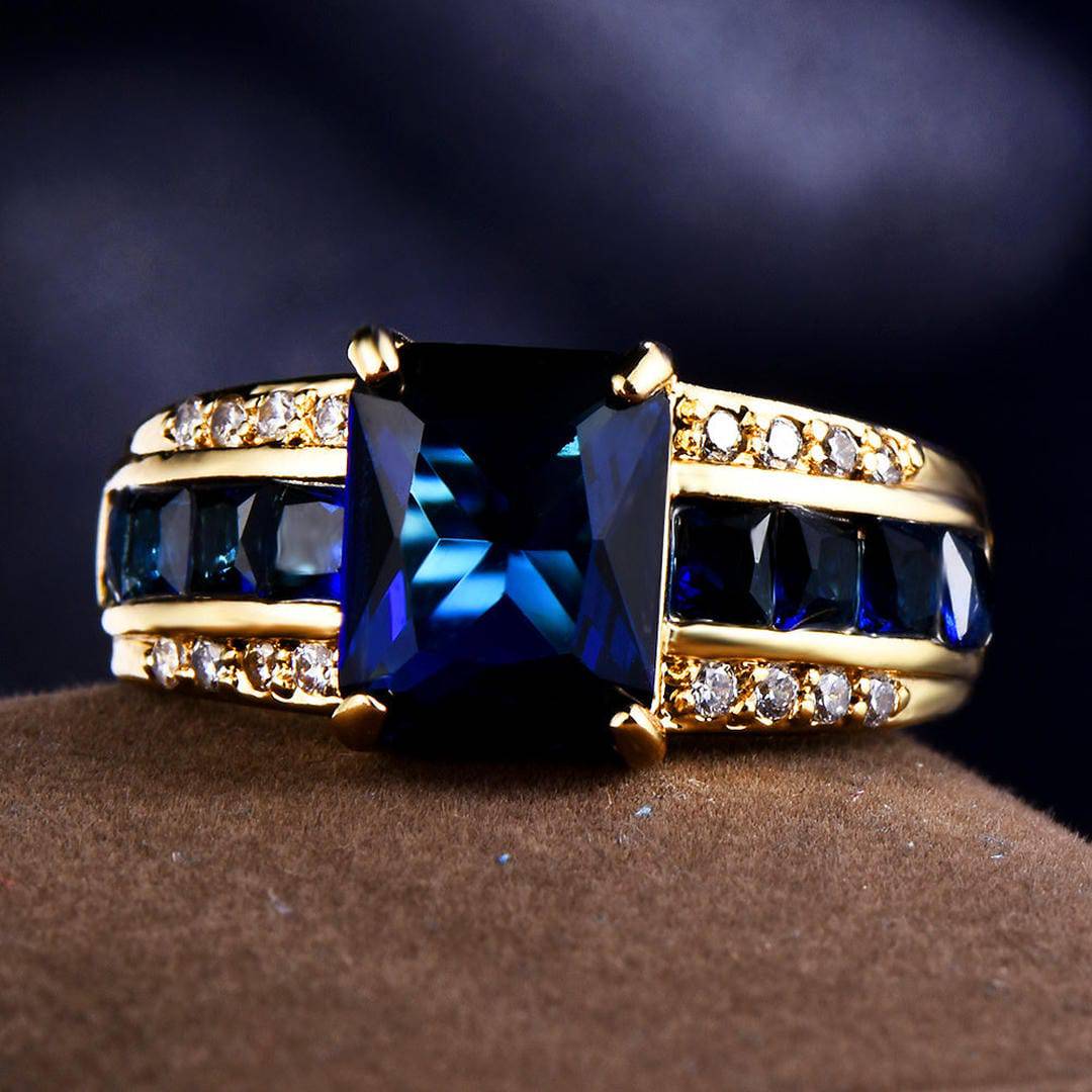 Bague en or, pierre centrale bleue rectangulaire, pierres latérales carrées et pavé