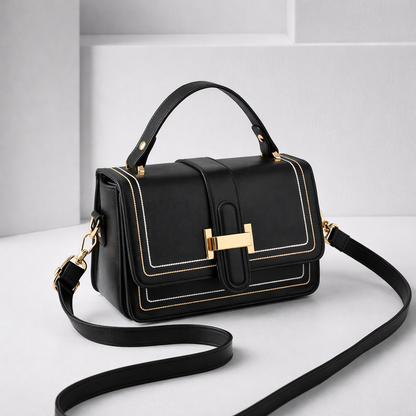 Sac à main en cuir noir à rabat, surpiqûres et fermoir doré rectangulaire.