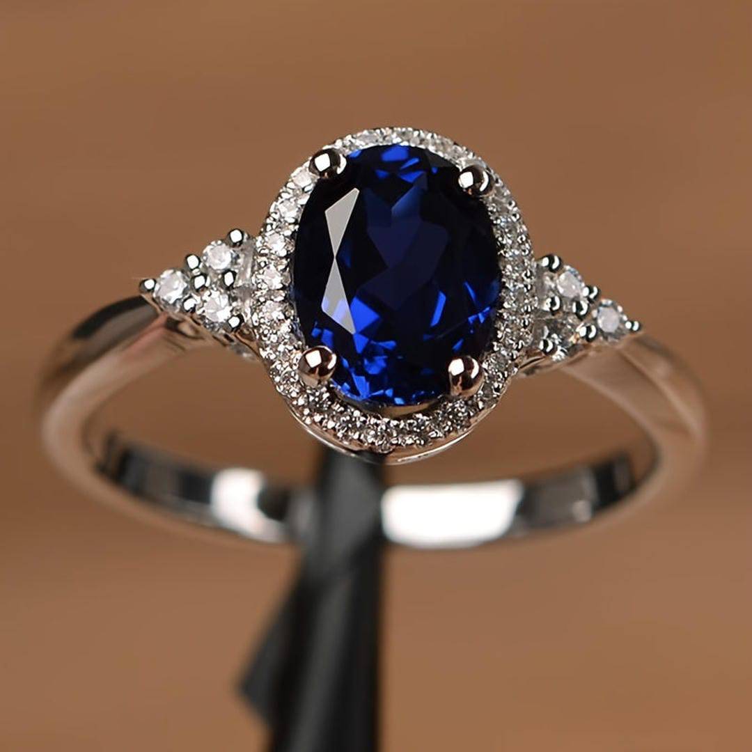 Bague saphir ovale bleu nuit, monture argent, entourage de pierres et griffes