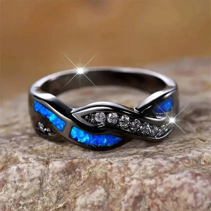 Bague Thessia Lunebray noire, inserts bleu opale et rangée de pierres brillantes.