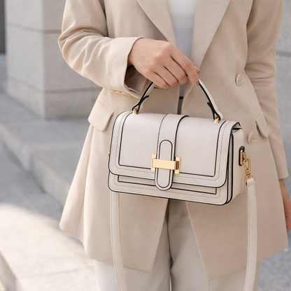 Sac à main en cuir beige clair à rabat, fermoir doré et bandoulière, porté.