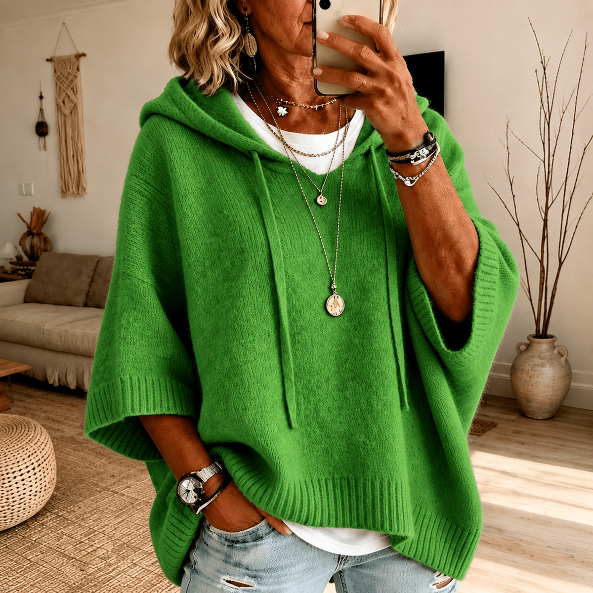 Poncho-pull vert à capuche en maille, manches larges et poche kangourou.