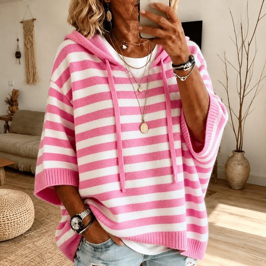 Poncho-pull rayé rose et blanc, capuche avec cordons, coupe ample, manches chauve-souris.