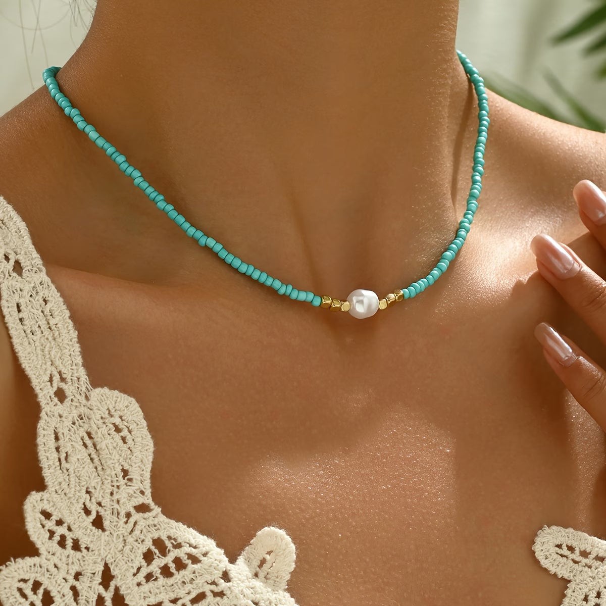 Collier minimaliste turquoise avec perle blanche centrale, gros plan, intercalaires dorés