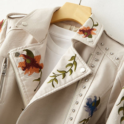 Veste en cuir blanc près du col, fermeture zippée et broderies multicolores.