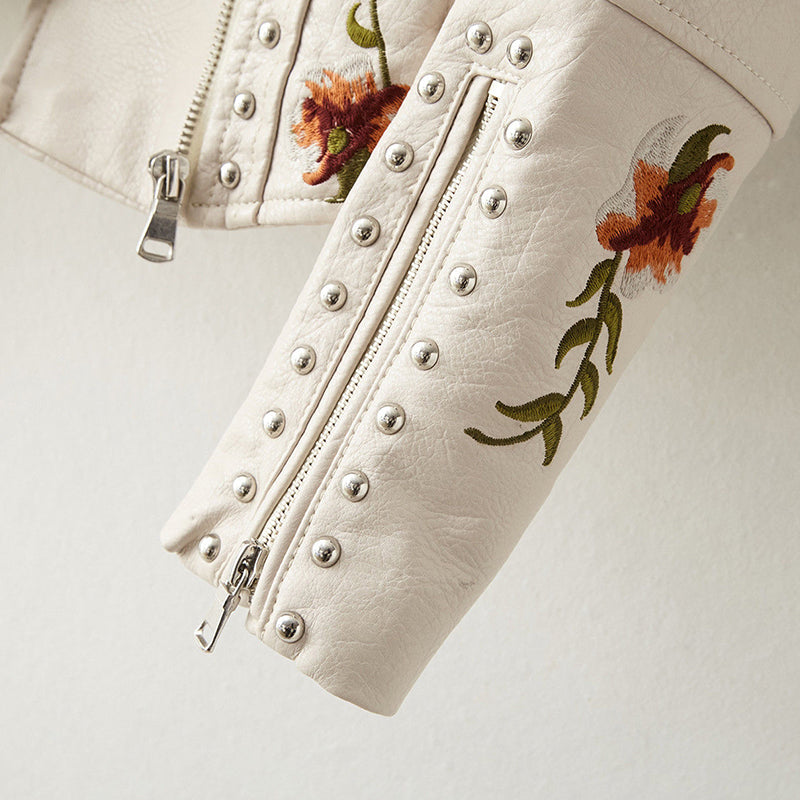 Veste en cuir blanc, bas de manches avec zips, boutons rivetés et fleurs brodées.
