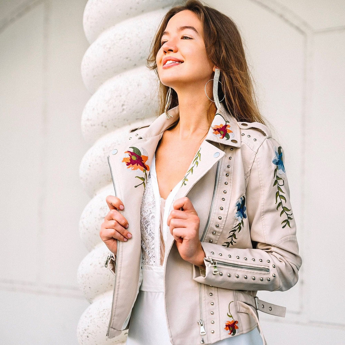 Veste en cuir blanc fleurie rétro, boutons rivetés et fermeture zippée sur le devant.
