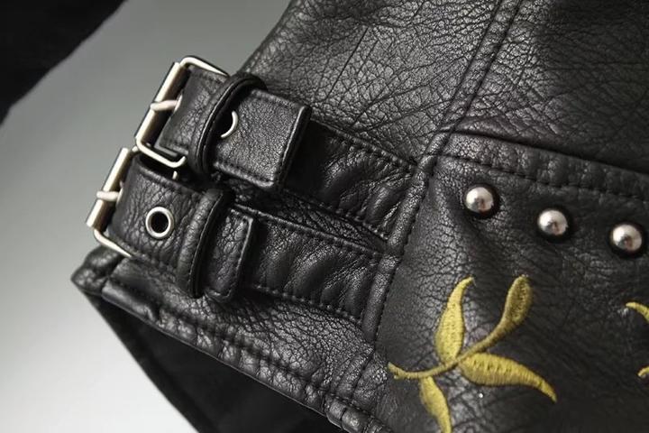 Veste en cuir noir, ceinture à boucle et broderie florale jaune sur le devant.
