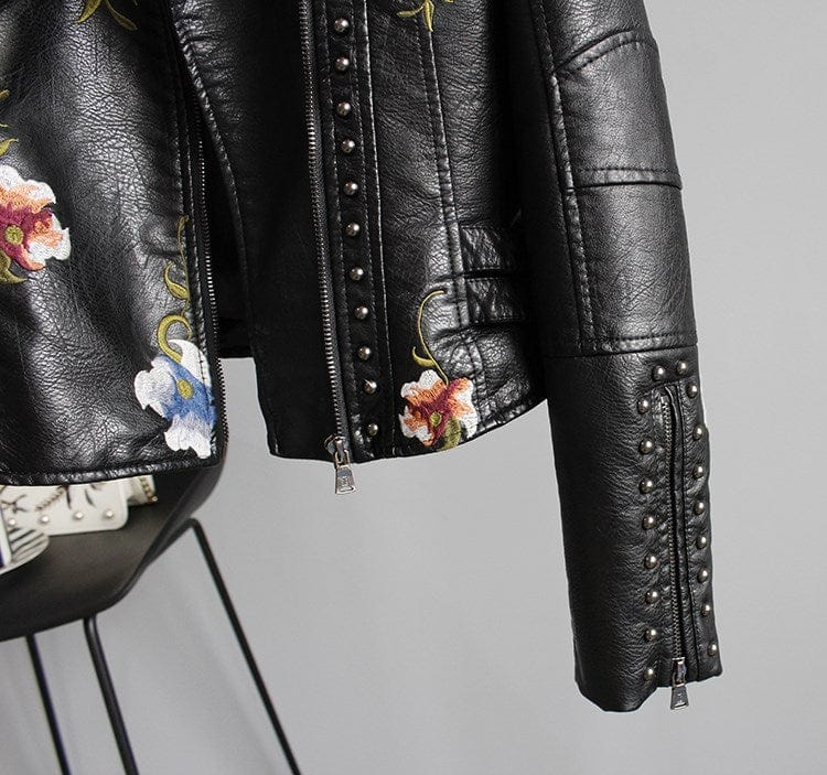 Veste en cuir noir, fermeture zippée centrale et broderies fleuries sur la poitrine.
