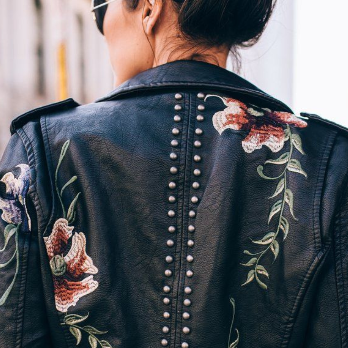 Dos de veste en cuir noir avec broderies florales et rangée de clous au centre