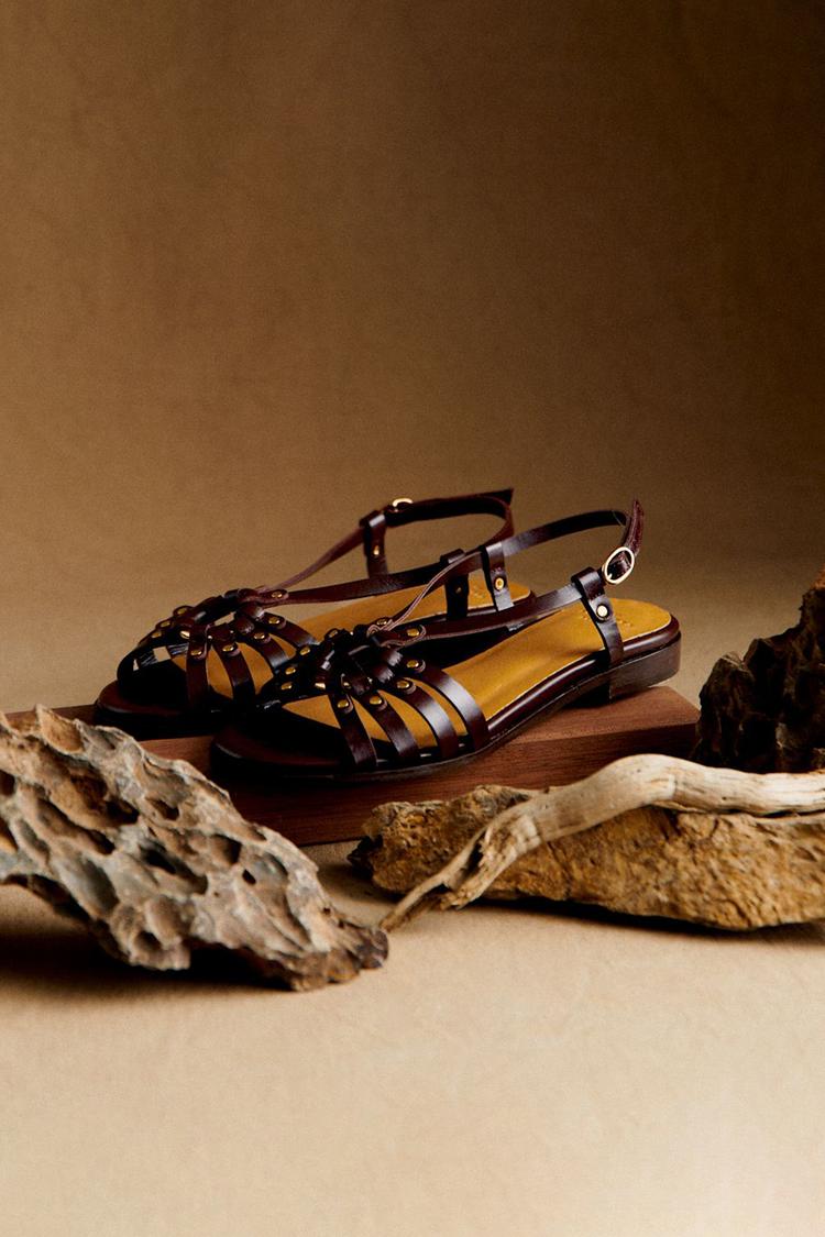 Sandales artisanales Terre d'Été noires posées sur des branches, brides multiples