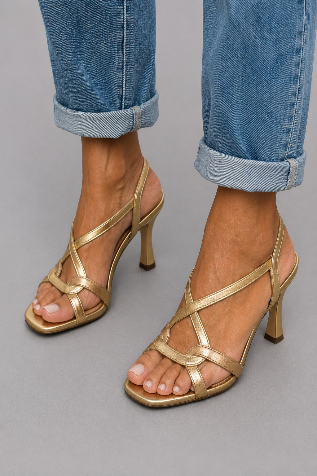 Sandales dorées à talon mi-haut, brides croisées, bout ouvert, portées avec jean