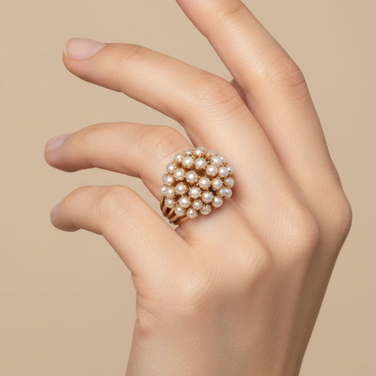 Bague dorée à grappe de perles nacrées, portée sur la main