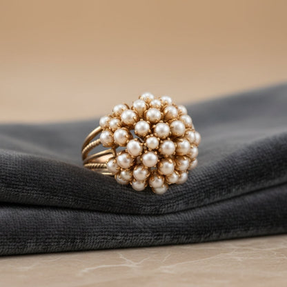 Bague dorée à grappe de perles nacrées sur tissu foncé