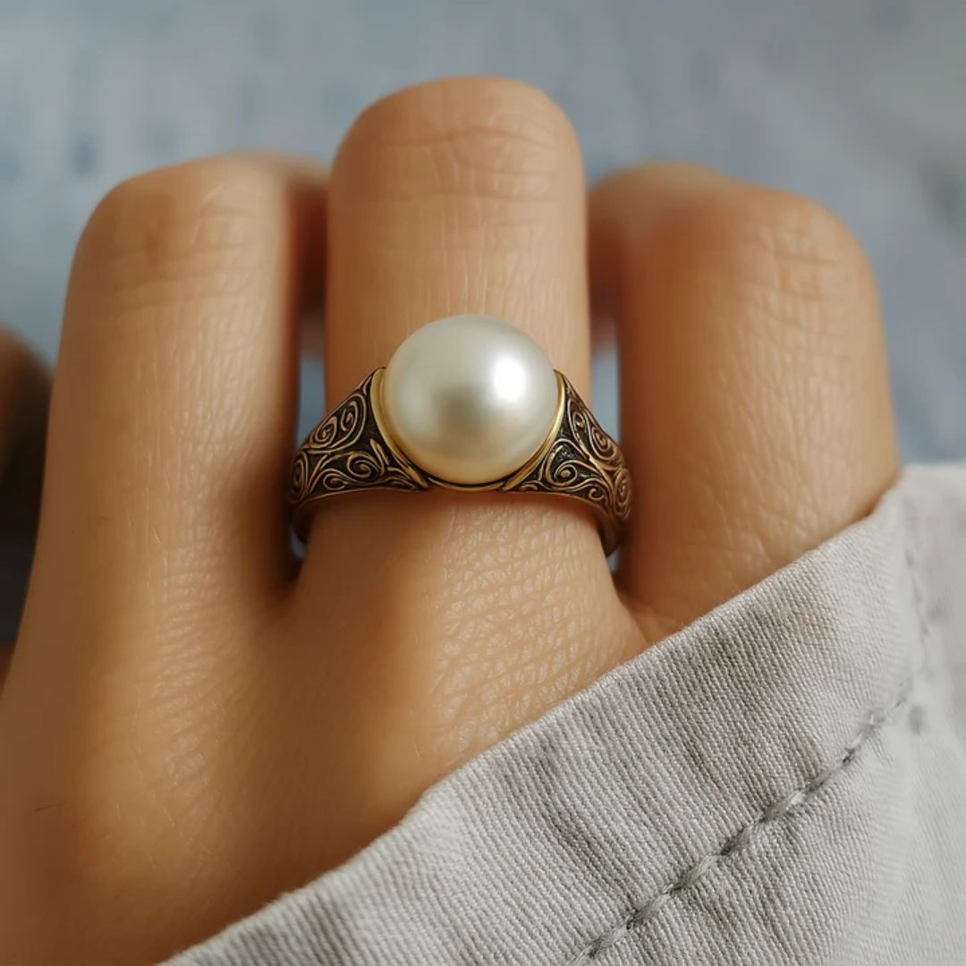 Bague dorée vintage à perle nacrée, motif gravé, portée sur un doigt