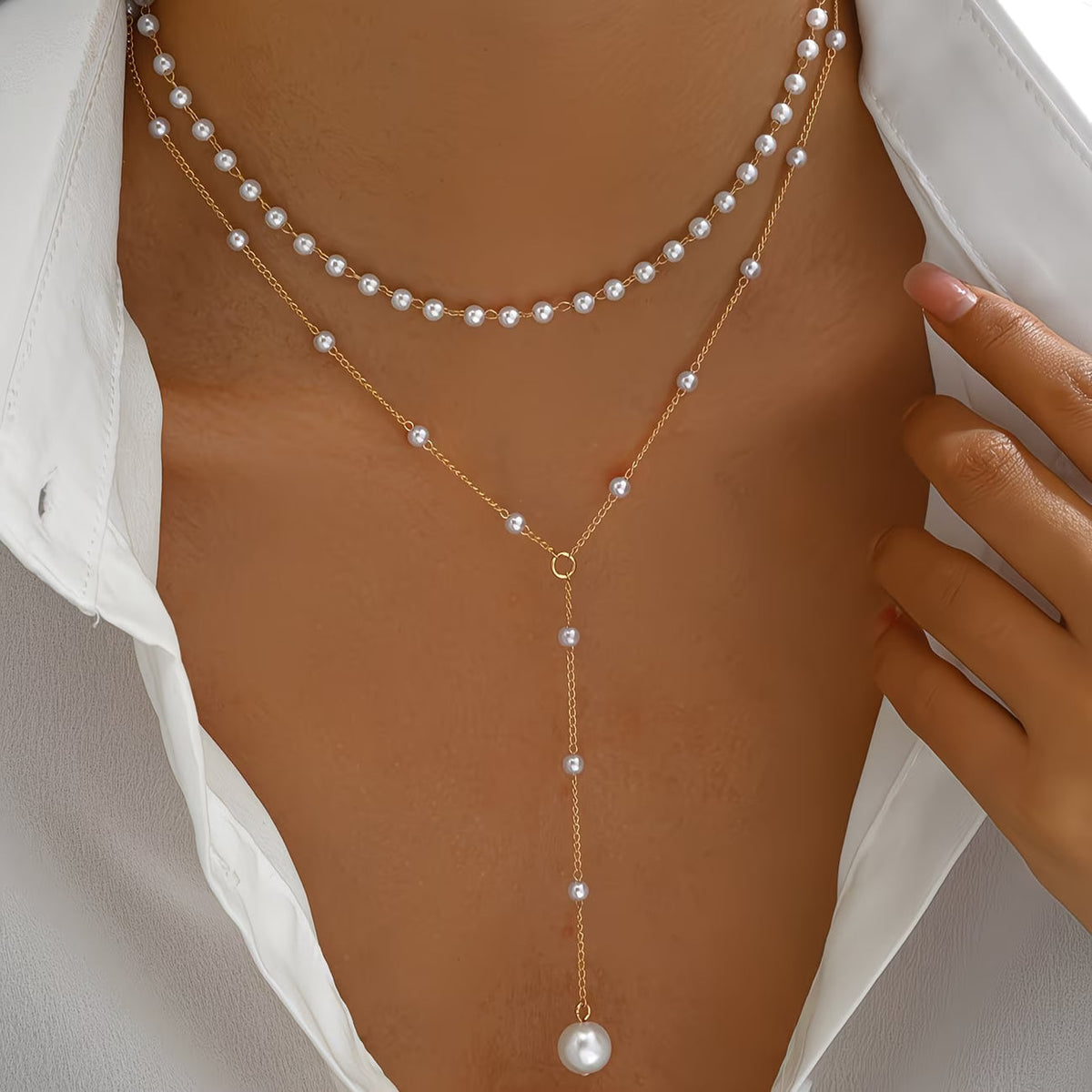 Collier à plusieurs rangs de perles blanches, chaîne dorée et pendentif perle