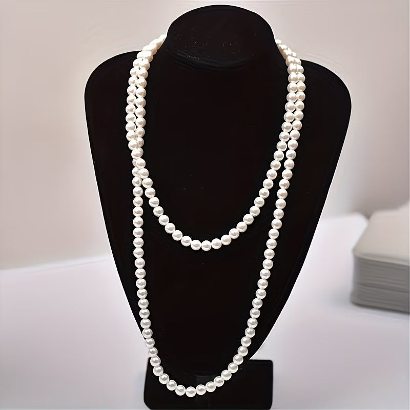 Collier double rang de perles nacrées blanches, porté sur buste noir.