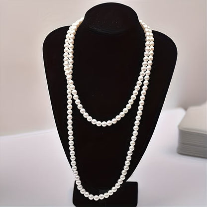 Collier double rang de perles nacrées blanches, porté sur buste noir.