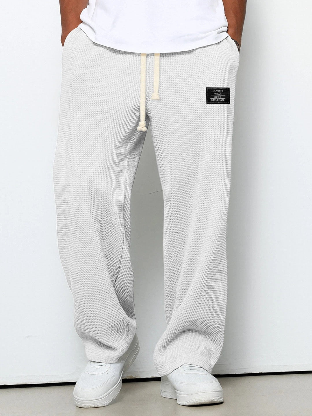 Pantalon ample blanc cassé à taille élastique et cordon, étiquette sur la hanche.