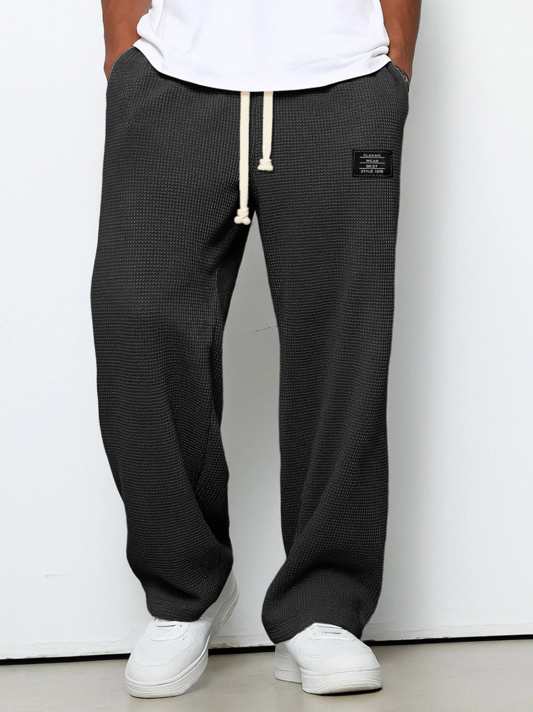 Pantalon ample noir à taille élastique et cordon, étiquette rectangulaire sur la hanche.