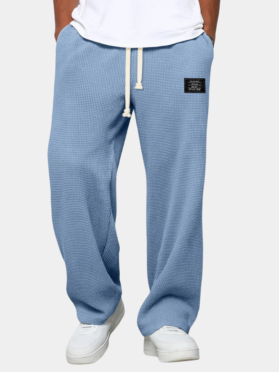Pantalon ample bleu à taille élastique et cordon, étiquette rectangulaire sur le côté.