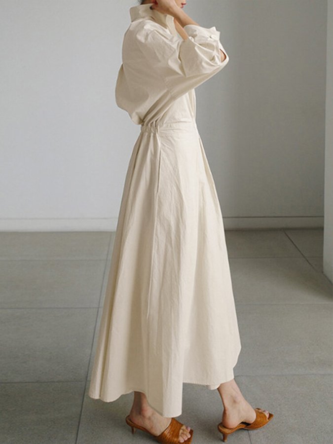 Robe longue beige à encolure V, manches bouffantes et ceinture à nouer.