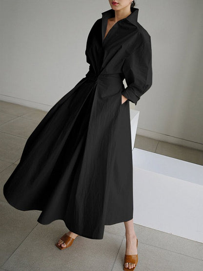 Robe longue noire à col chemise, manches bouffantes et ceinture nouée.