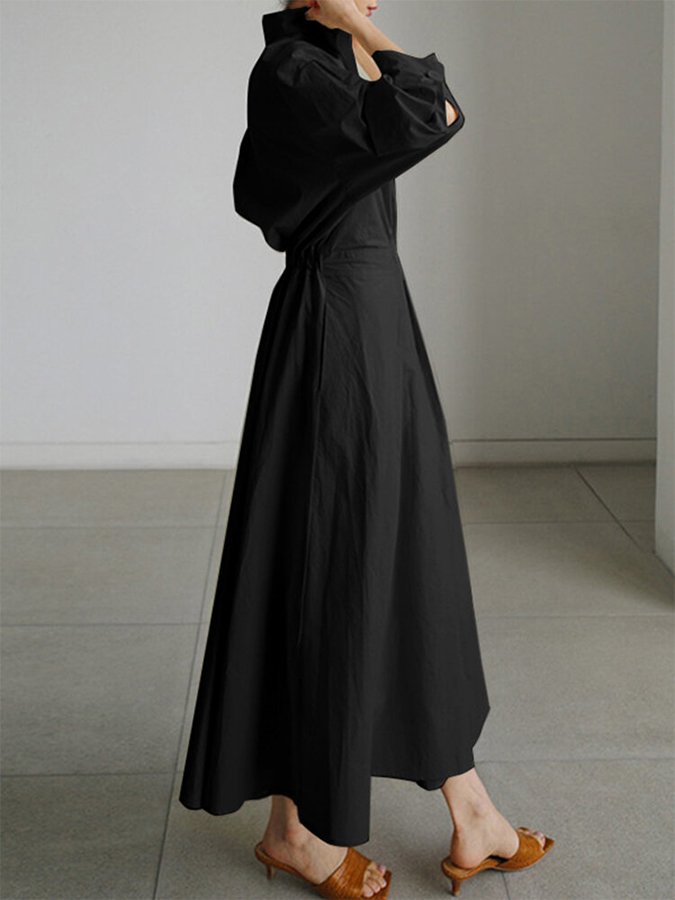 Robe longue noire cintrée, col en V, manches bouffantes et ceinture.