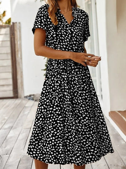 Robe fluide midi noire à motifs taches blanches, col V, manches courtes.