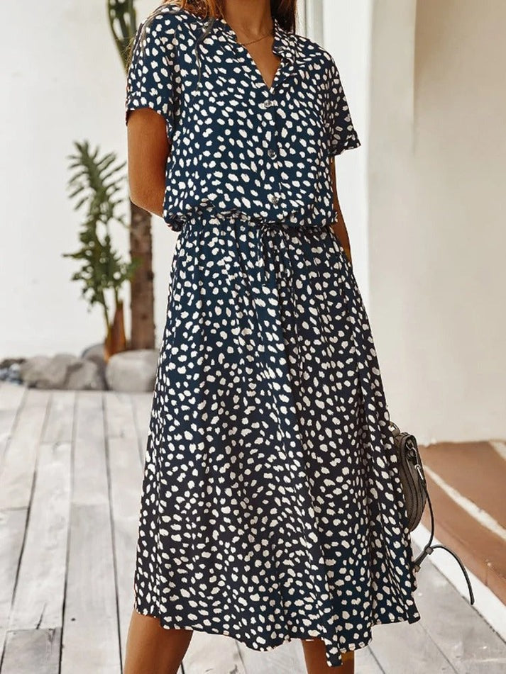 Robe fluide midi bleu marine à motif taches blanches, col V boutonné, manches courtes.