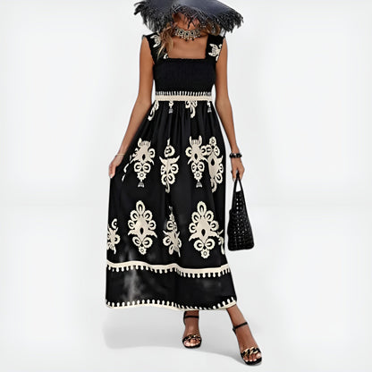 Robe d’été noire sans manches, motifs blancs baroques, taille smock et ourlet contrasté.