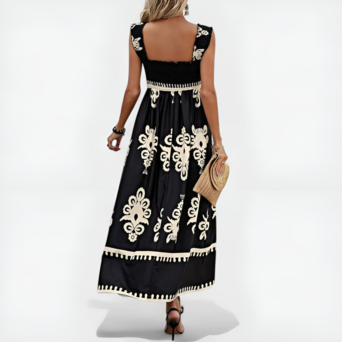 Robe d’été noire sans manches, encolure carrée dos nu, motifs blancs et bordure à pompons.
