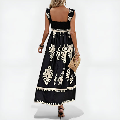 Robe d’été noire sans manches, encolure carrée dos nu, motifs blancs et bordure à pompons.