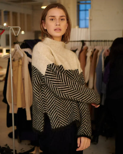 Pull beige et noir à col montant, grand motif chevrons, manches longues, coupe droite.
