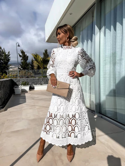 Robe en dentelle romantique blanche, manches longues bouffantes, col haut, motif ajouré.