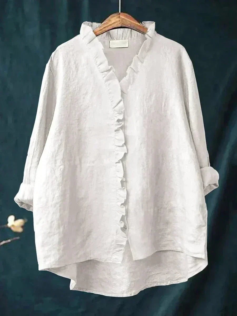 Blouse blanche à encolure V, volants boutonnés et manches longues froncées.