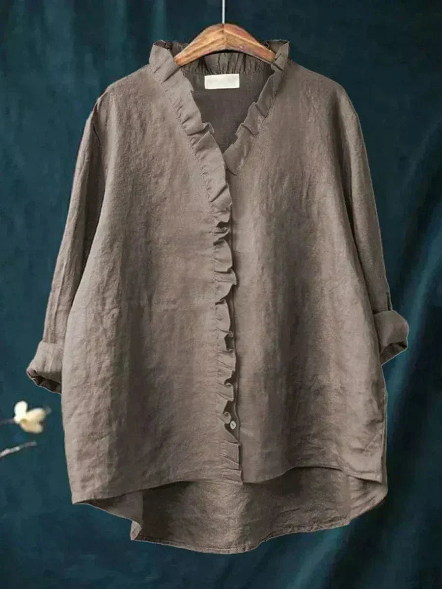 Blouse gris foncé à encolure V et volants boutonnés, manches longues froncées.