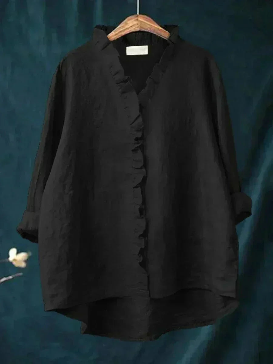 Blouse noire à encolure V avec volants boutonnés, manches longues froncées.