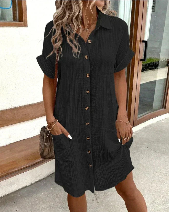 Robe polo noire ceinturée, manches courtes, patte boutonnée et poches latérales.