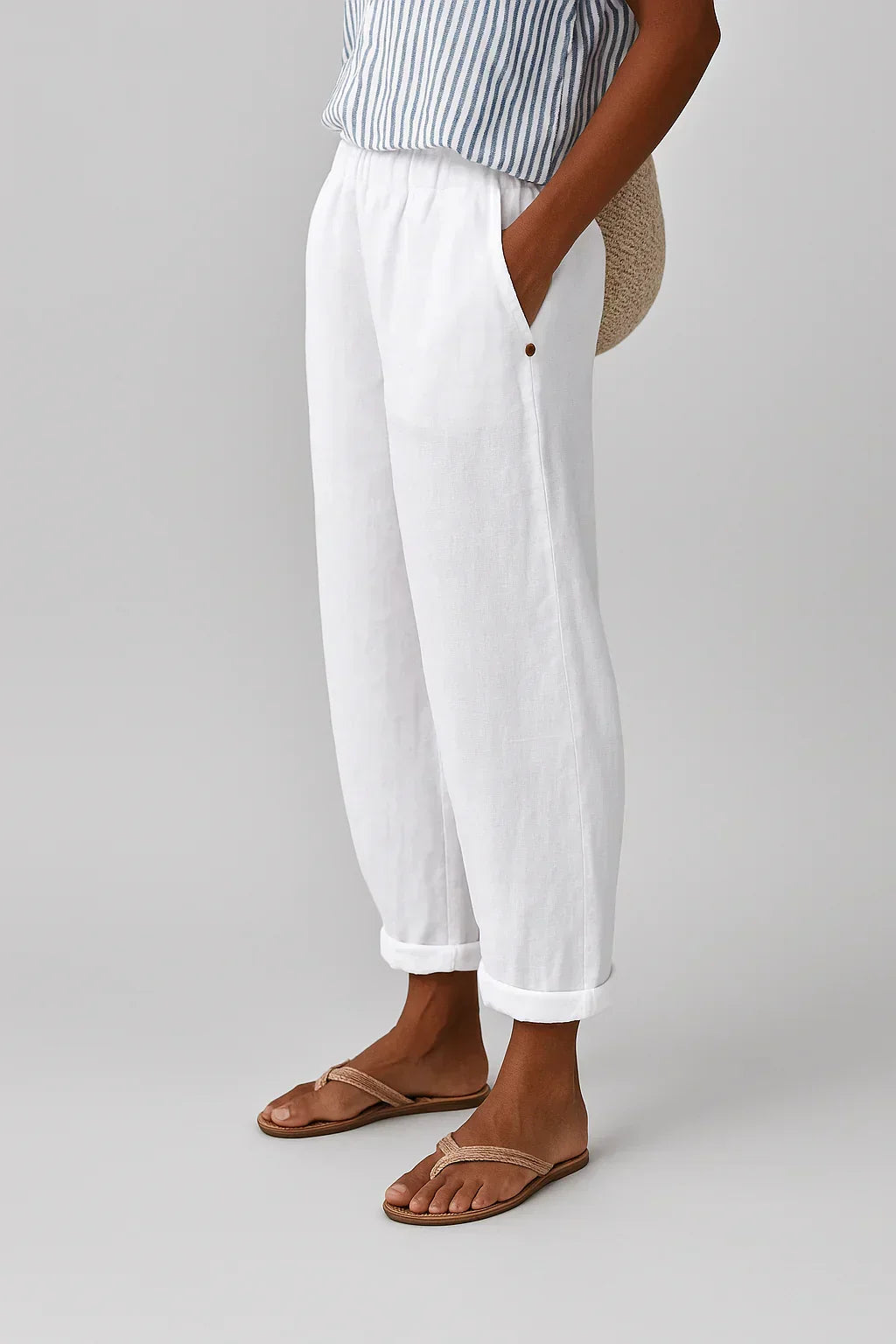 Pantalon en lin-coton blanc, taille élastique, bas retroussés, bouton décoratif.