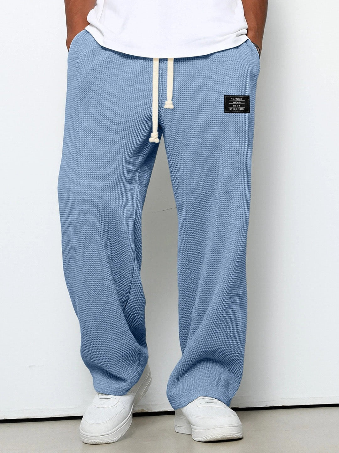 Pantalon large bleu à taille réglable, cordon à la ceinture, jambe ample, tissu texturé.