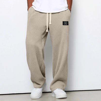 Pantalon large kaki à taille réglable, cordon à la ceinture, jambe ample, tissu texturé.