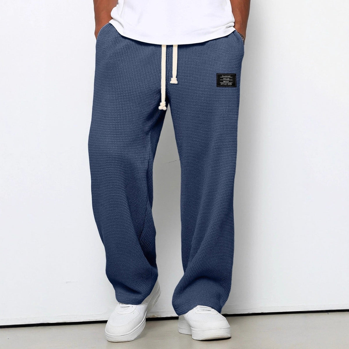 Pantalon large bleu à taille réglable, cordon à la ceinture, jambe ample, tissu texturé.