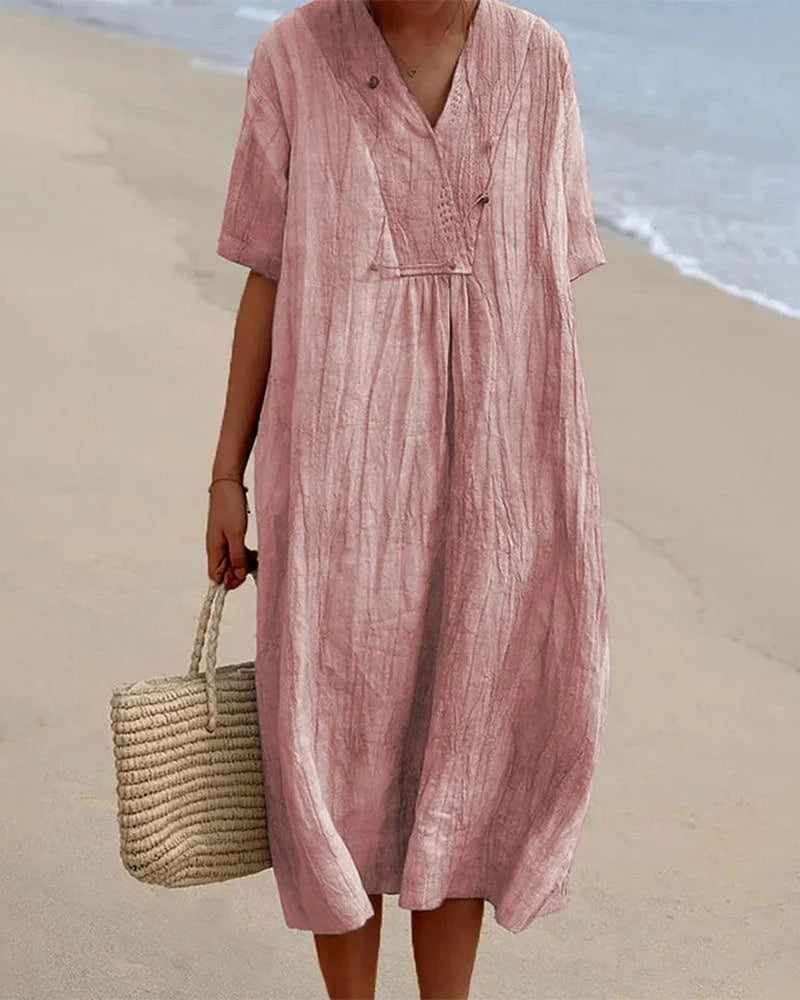 Robe mi-longue rose, encolure V, manches courtes, boutons et poche plaquée.
