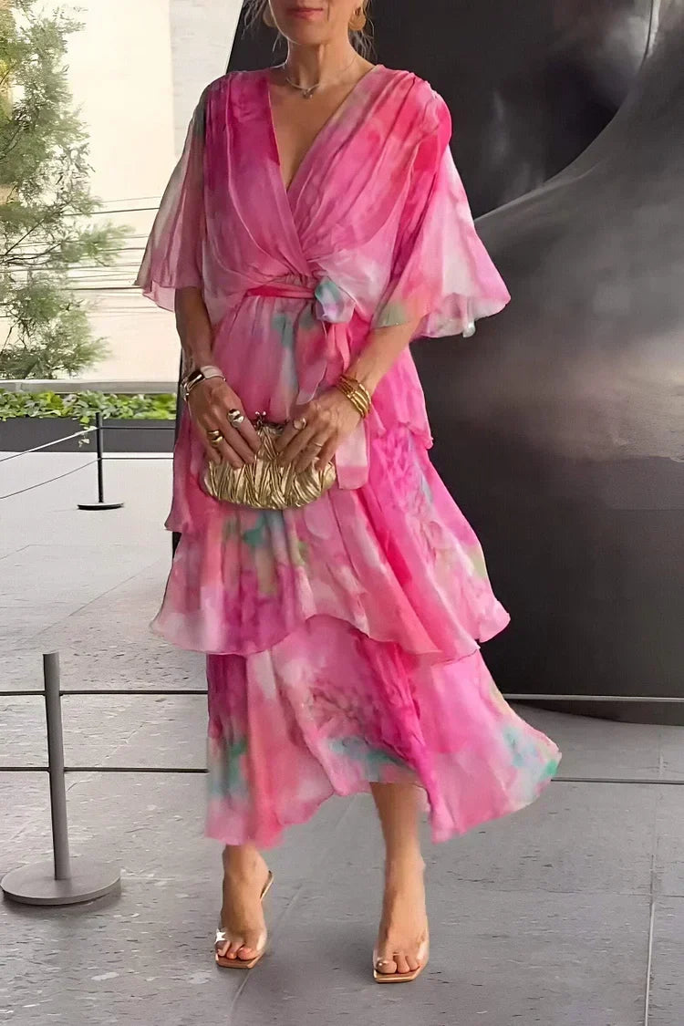 Robe en chiffon rose dégradé, décolleté en V, volants superposés et ceinture nouée.